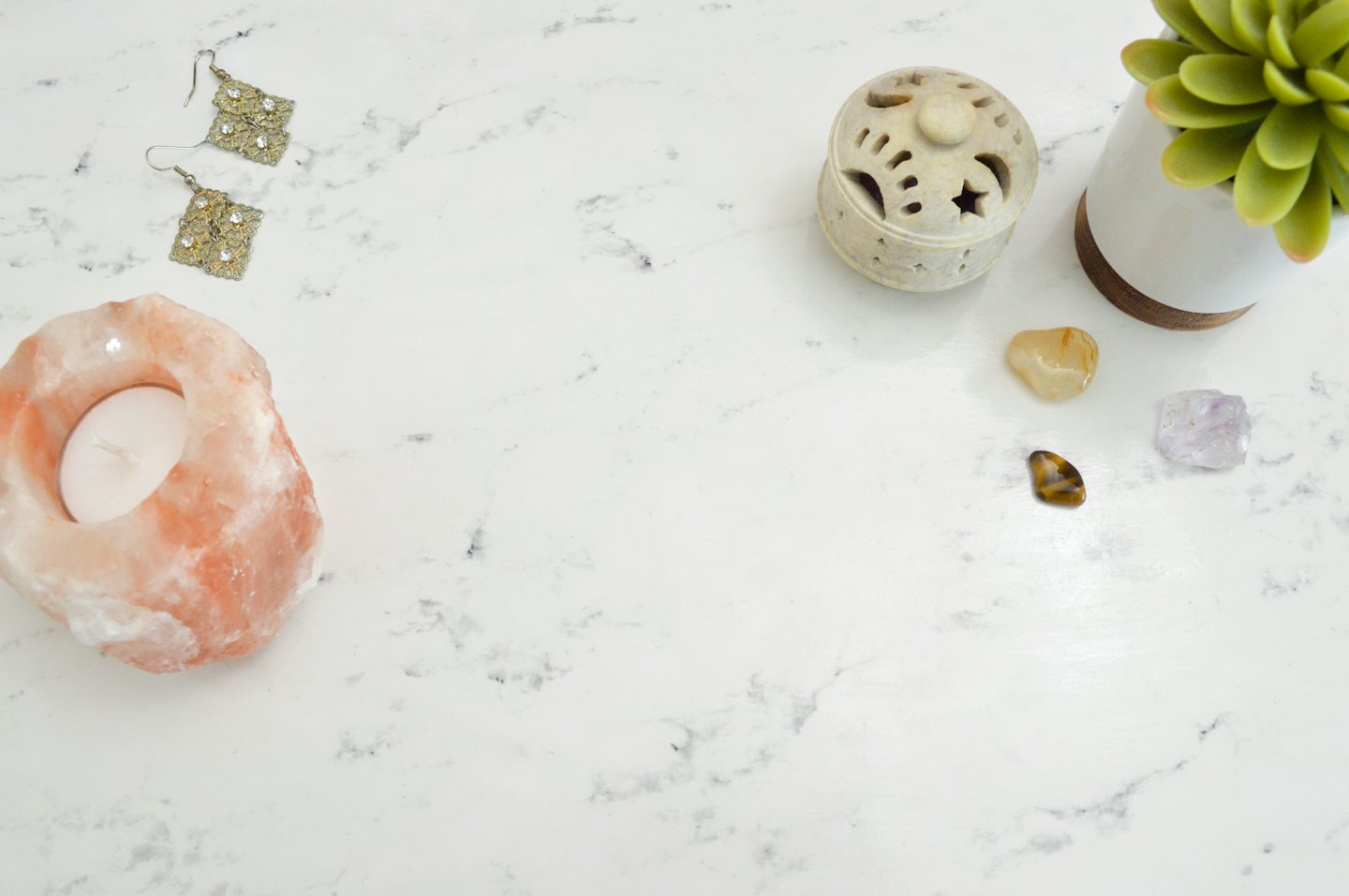 Himalayan salt lamp, jewelry, and crystals arranged on white marble.